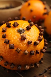 Photo of Pomander ball made of tangerine with cloves on wooden table, closeup