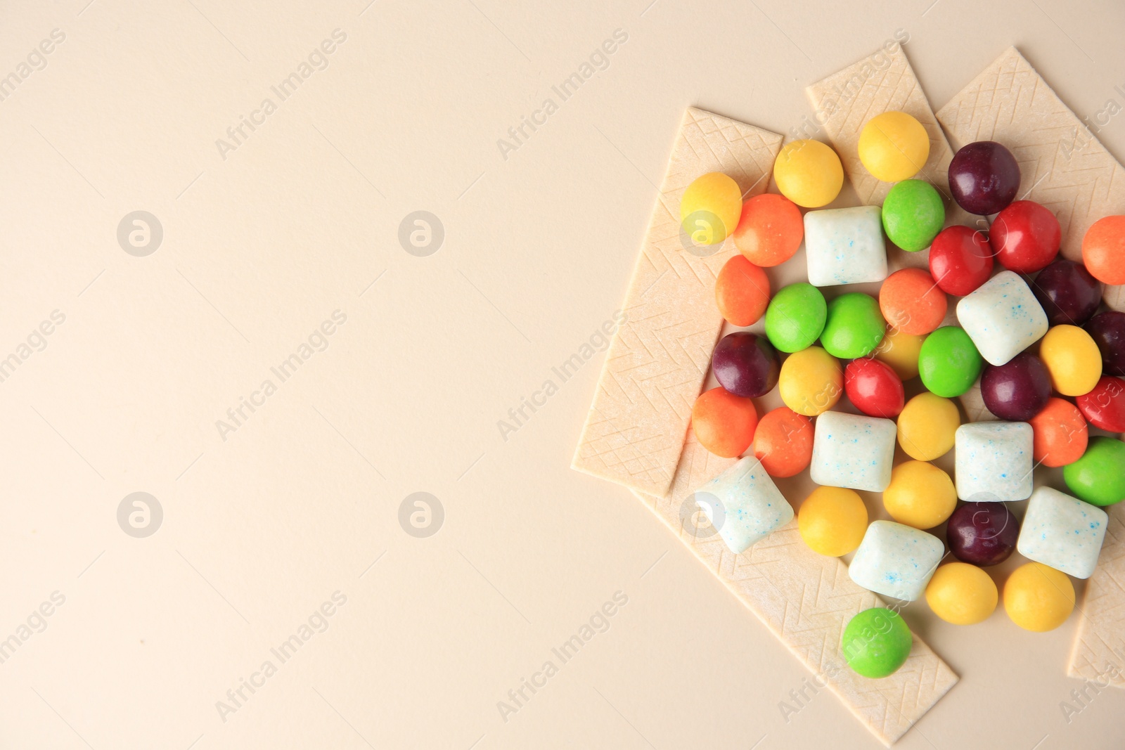 Photo of Different tasty chewing gums on beige background, flat lay. Space for text