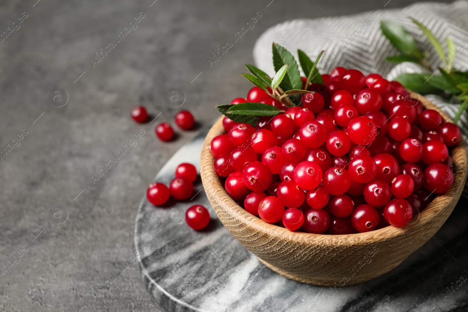 Photo of Tasty ripe cranberries on grey table, closeup. Space for text