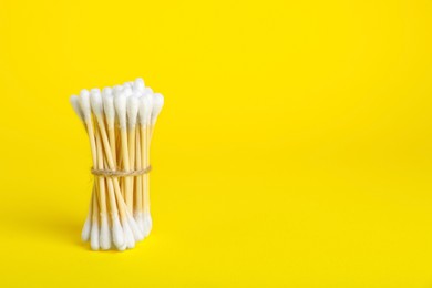 Bunch of new cotton buds on yellow background. Space for text