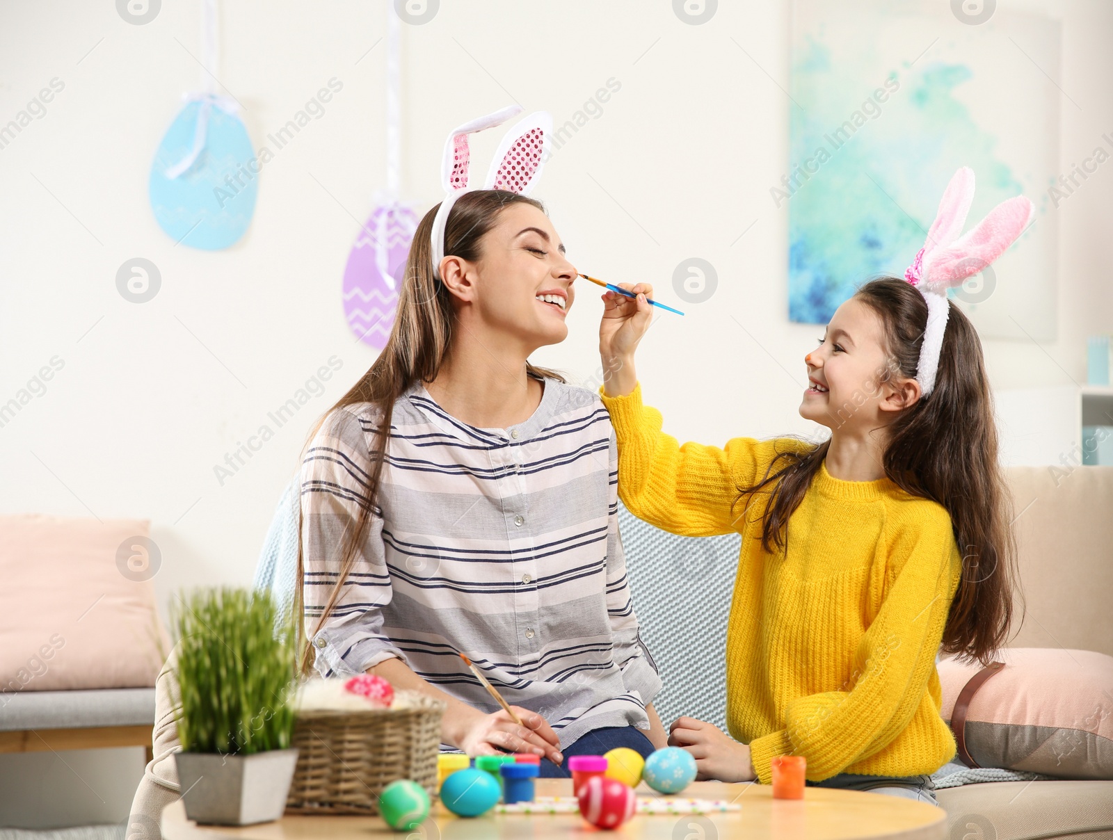 Photo of Mother and daughter with bunny ears headbands having fun at home. Easter holiday