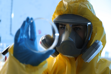 Scientist in chemical protective suit with Petri dish at laboratory. Virus research