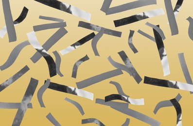 Image of Shiny silver confetti falling on pale orange background