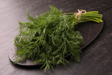 Photo of Bunch of fresh dill on dark textured table, closeup