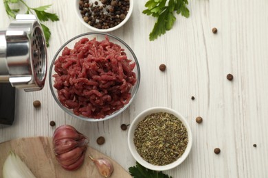 Meat grinder, beef mince, garlic, parsley and spices on white wooden table, flat lay