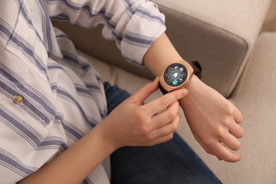 Image of Woman setting smart home control system via smartwatch indoors, closeup. App interface with icons on display