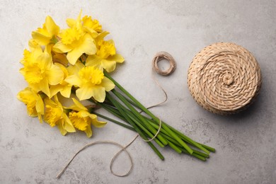 Beautiful daffodils, twine and wicker box on grey table, flat lay