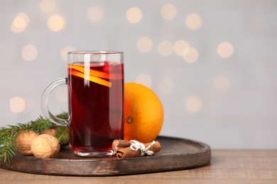 Photo of Aromatic mulled wine in glass cup on table against grey background with blurred lights, closeup. Space for text