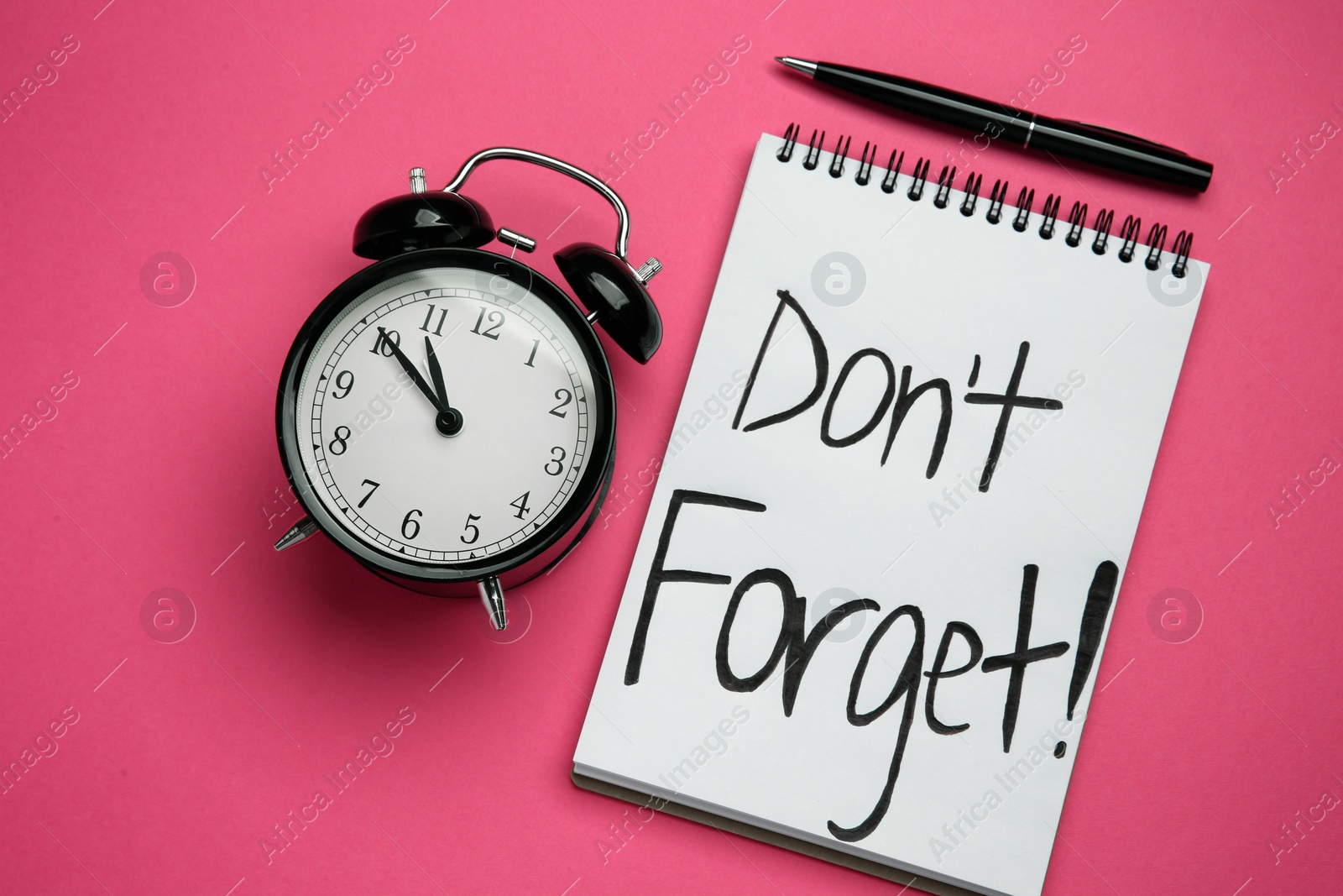 Photo of Alarm clock, pen and notebook with text Don't forget on pink background, flat lay. Reminder concept