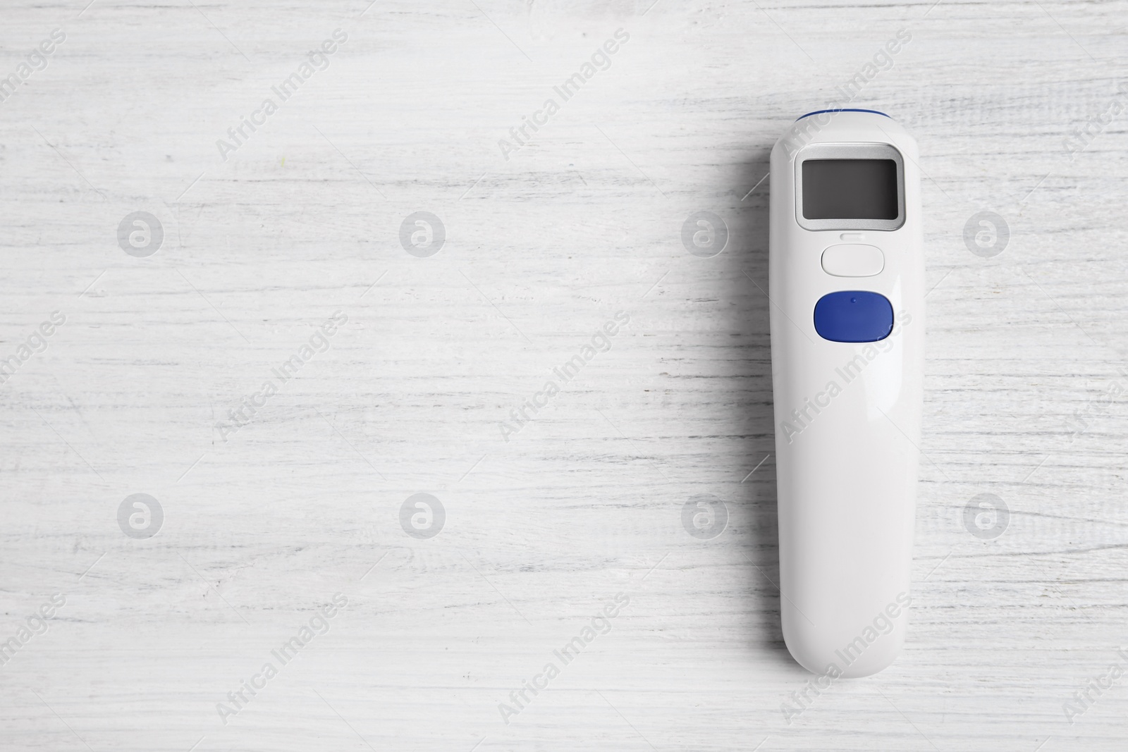 Photo of Modern non-contact infrared thermometer on white wooden background, top view. Space for text