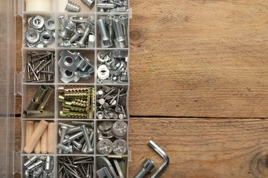 Organizer with many different fasteners on wooden table, flat lay. Space for text