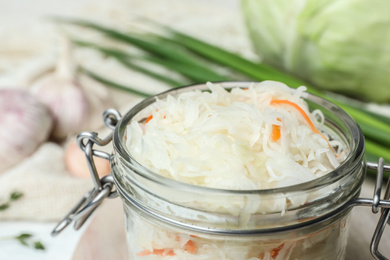 Photo of Jar of tasty fermented cabbage on table, closeup