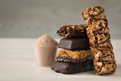 Photo of Different tasty energy bars and protein powder on white table, closeup