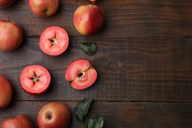 Tasty apples with red pulp and leaves on wooden table, flat lay. Space for text