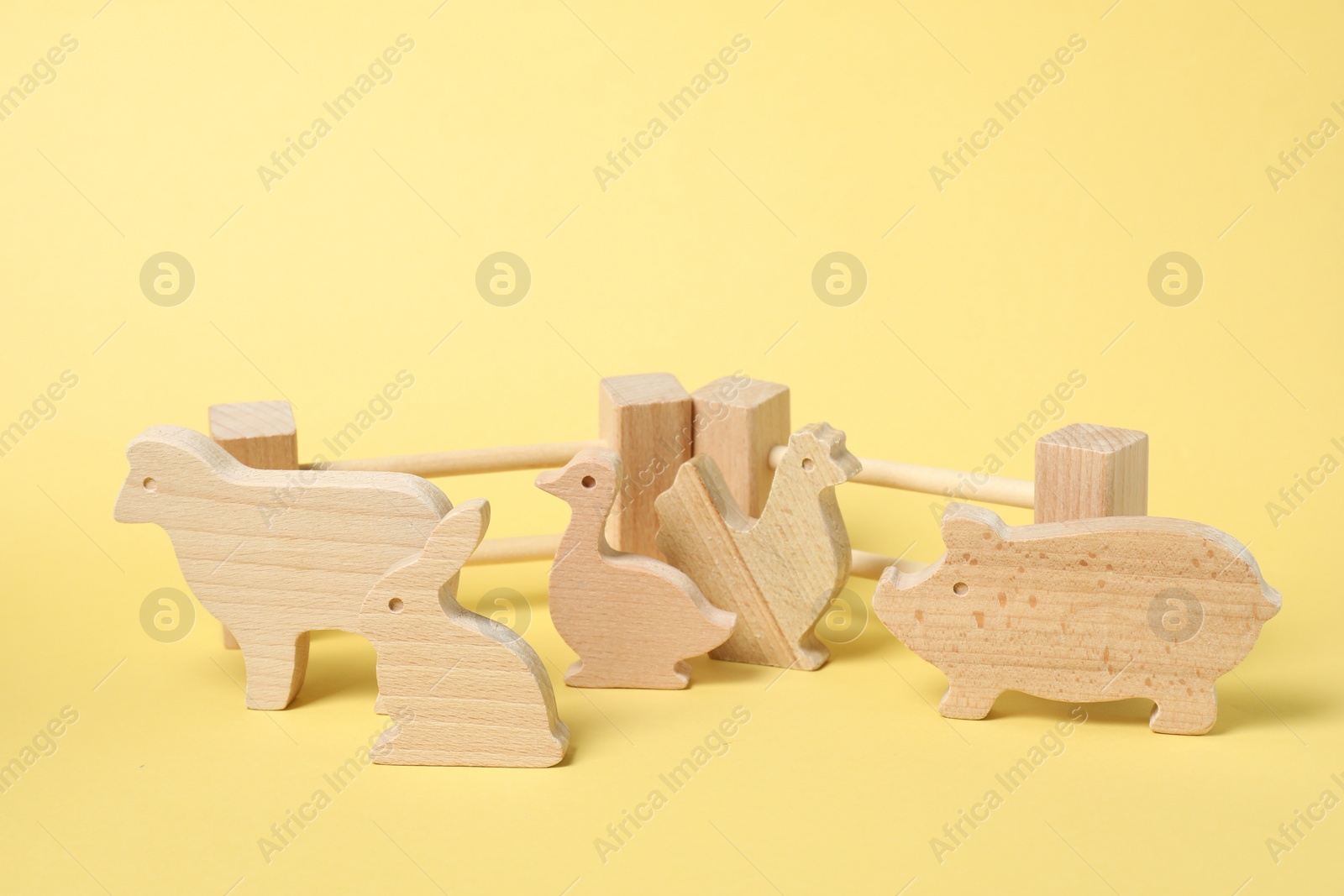 Photo of Wooden animals and fence on yellow background. Children's toy