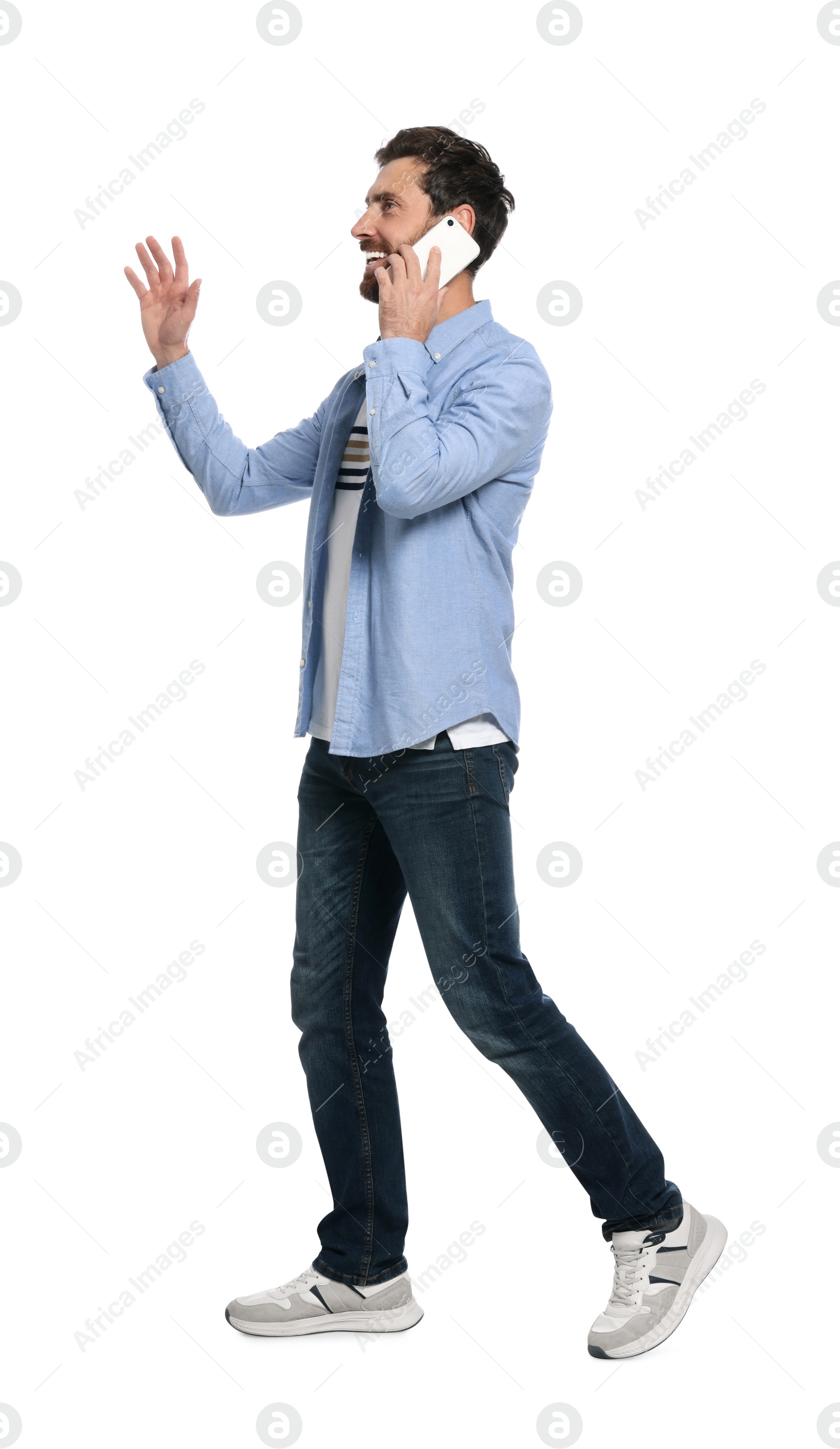 Photo of Handsome man talking on smartphone while walking against white background