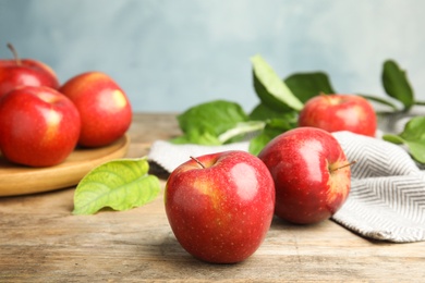 Photo of Ripe juicy red apples on wooden table against blue background. Space for text