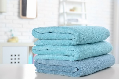 Stack of fresh towels on table in bathroom, closeup