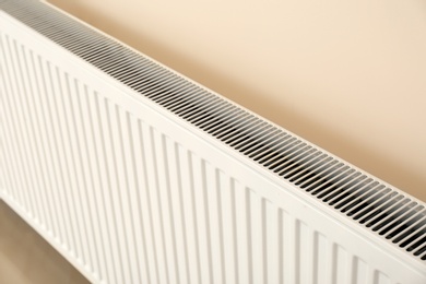 Photo of Modern heating radiator on light wall indoors