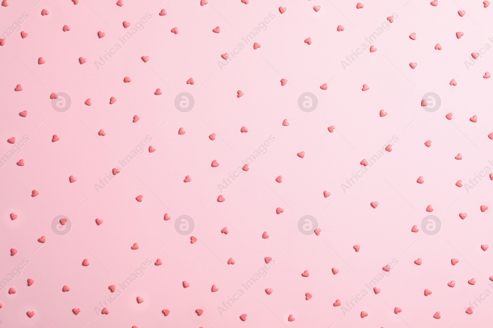 Photo of Tasty bright heart shaped sprinkles on pink background, flat lay