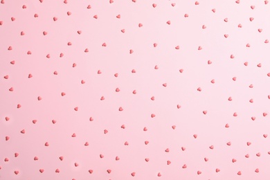 Photo of Tasty bright heart shaped sprinkles on pink background, flat lay
