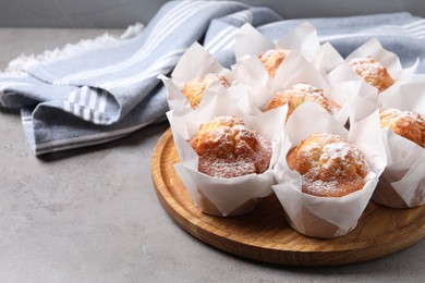 Delicious muffins with powdered sugar on grey table, closeup