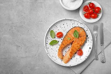 Plate with tasty salmon steak on grey background