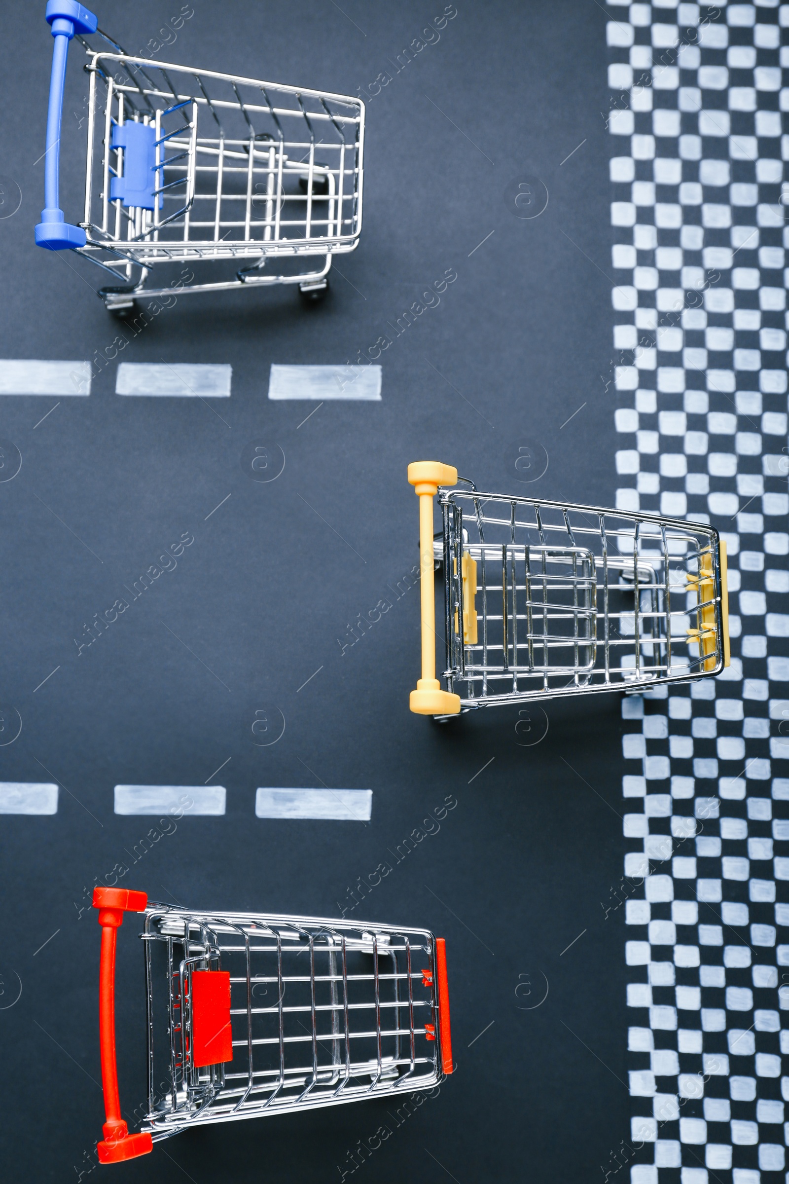 Photo of Competition concept. Shopping carts racing towards finish line, flat lay