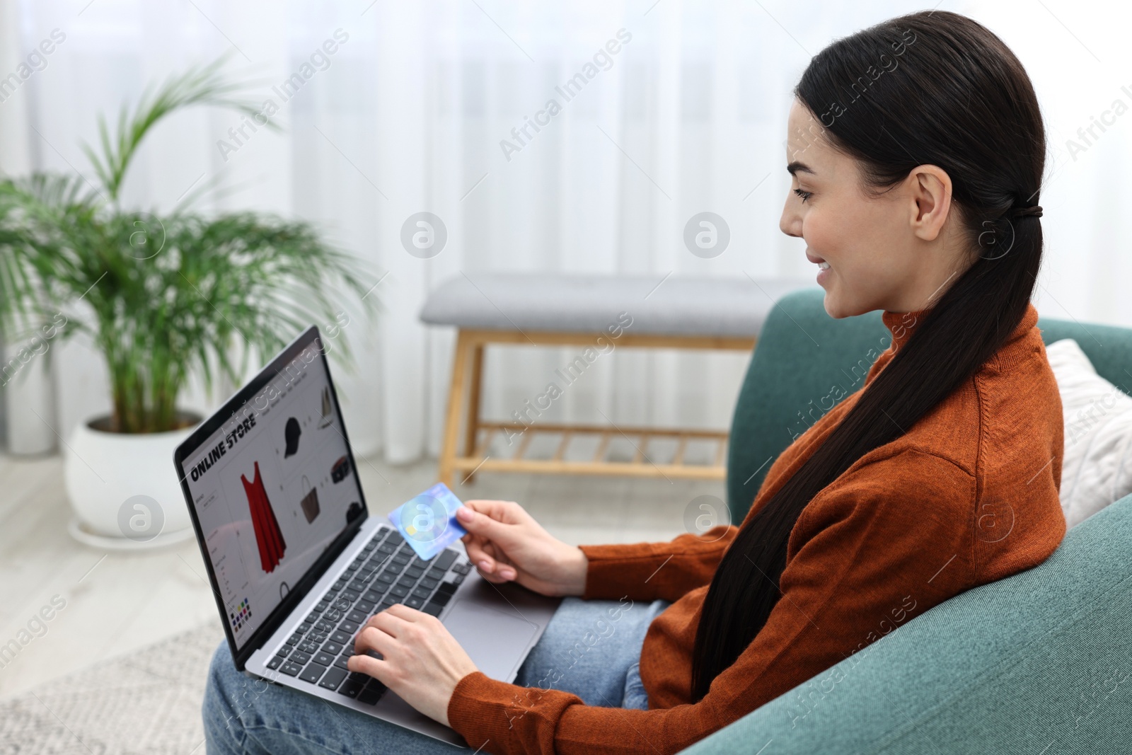 Photo of Beautiful young woman with laptop and credit card shopping online at home