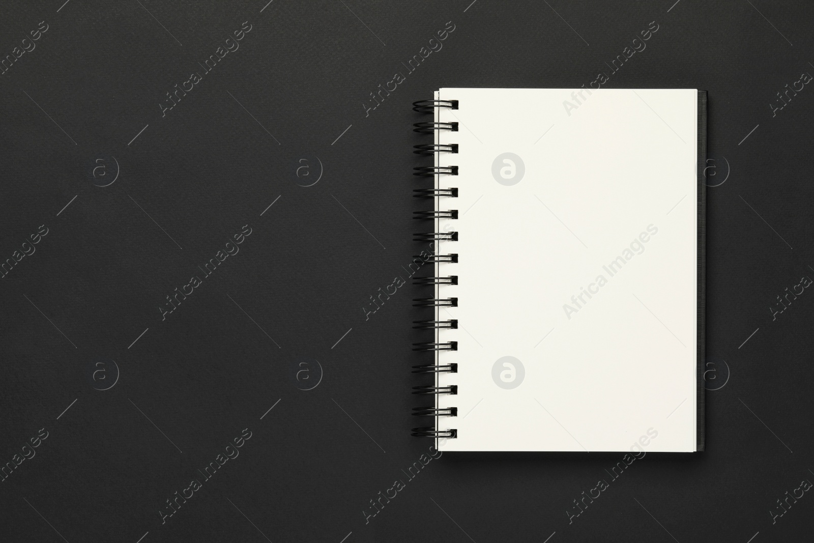 Photo of Blank notebook on black background, top view. Space for text