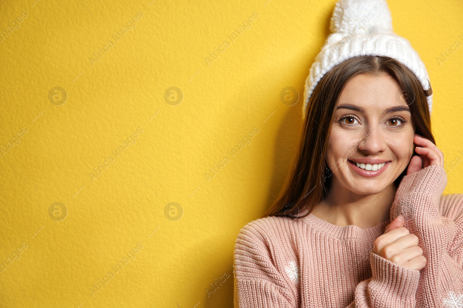 Photo of Beautiful young woman in warm sweater with hat on color background. Space for text