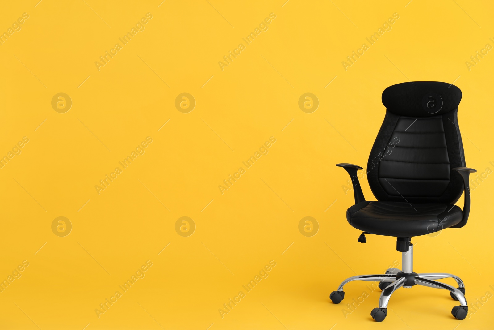 Photo of Modern office chair on yellow background. Space for text