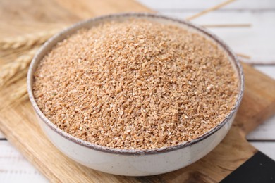 Photo of Dry wheat groats in bowl on table, closeup