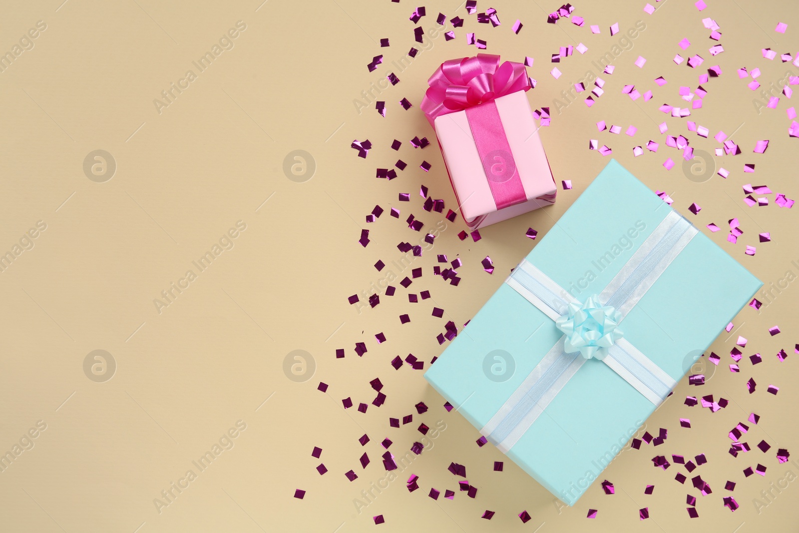 Photo of Gift boxes and shiny confetti on beige background, flat lay. Space for text