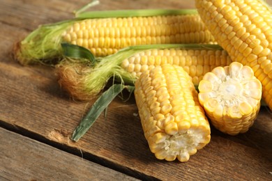 Tasty sweet corn cobs on wooden table, closeup