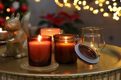 Burning candles on table in room decorated for Christmas