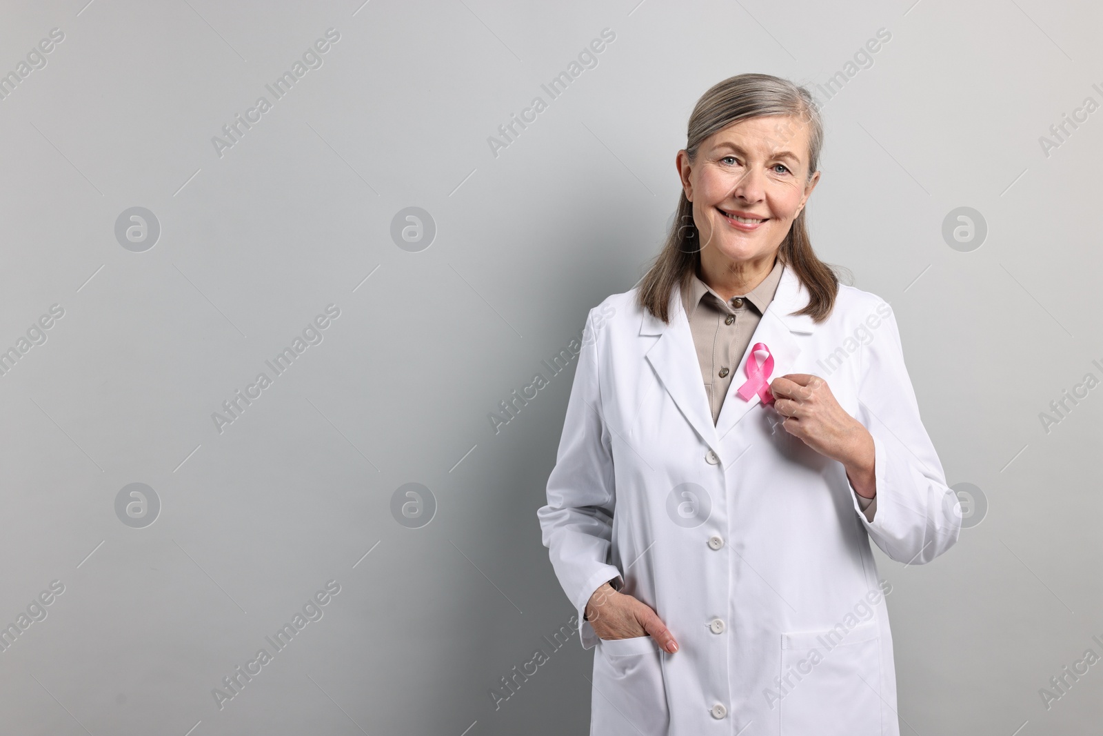 Photo of Mammologist with pink ribbon on gray background, space for text. Breast cancer awareness