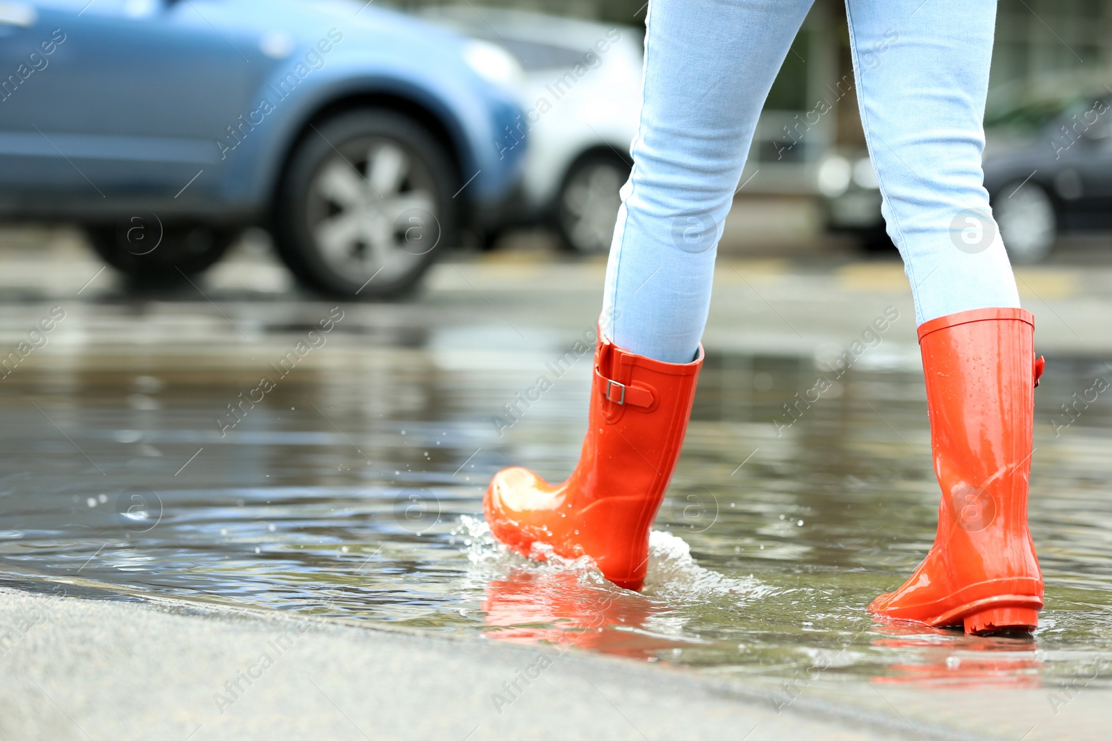 Photo of Woman with rubber boots in puddle, closeup. Rainy weather