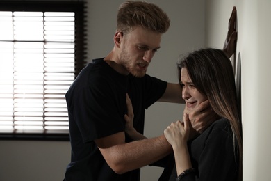 Man choking young woman indoors. Stop sexual assault