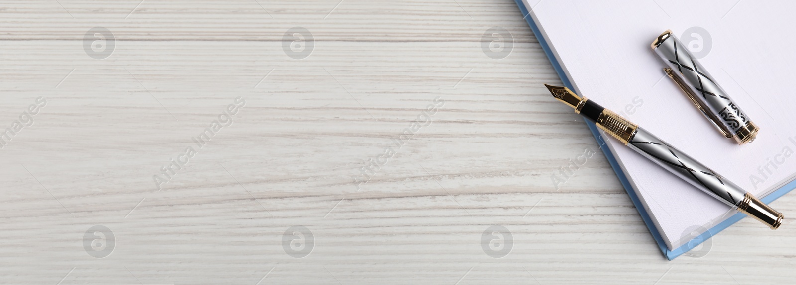 Image of Beautiful fountain pen and notebook on white wooden table, top view with space for text. Banner design