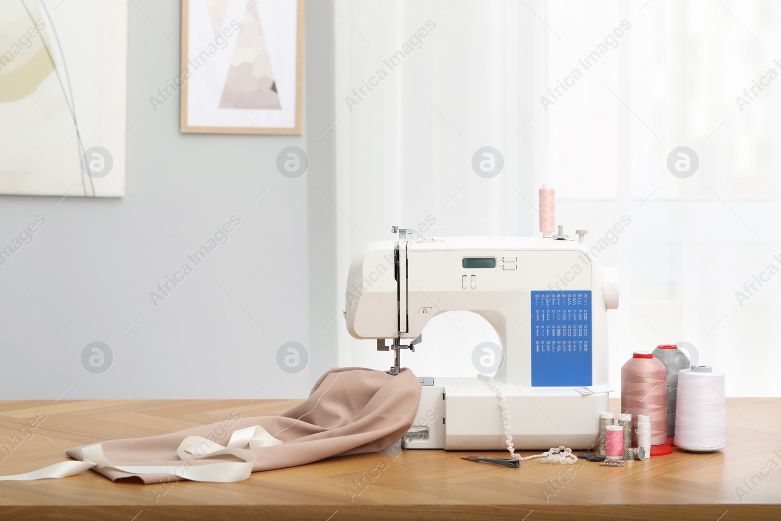 Photo of Sewing machine with fabric and craft accessories on wooden table indoors