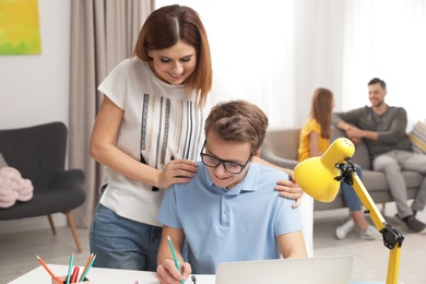 Photo of Mother helping her teenager son with homework indoors