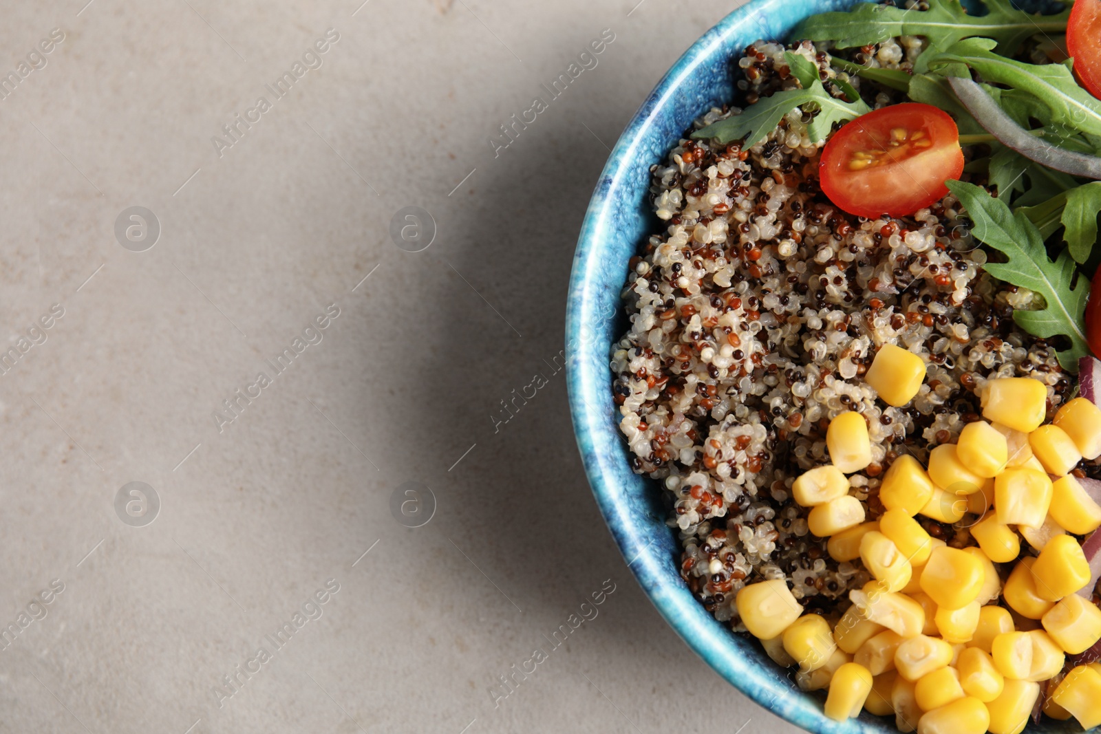 Photo of Healthy quinoa salad with vegetables in bowl on color background, top view. Space for text