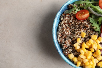 Photo of Healthy quinoa salad with vegetables in bowl on color background, top view. Space for text