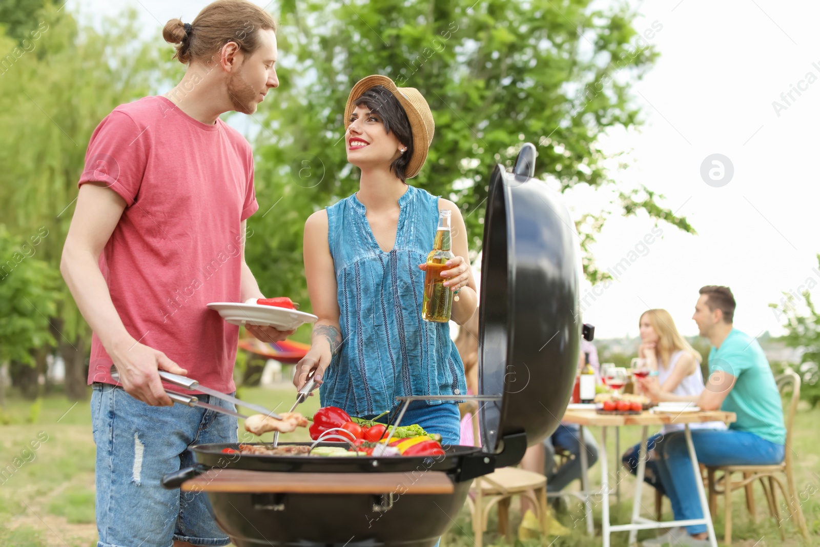 Photo of Young people having barbecue with modern grill outdoors