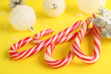Photo of Sweet Christmas candy canes on yellow background, closeup