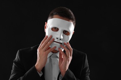 Photo of Multiple personality concept. Man in mask on black background