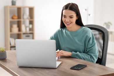 Young woman watching webinar at table in room