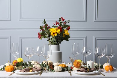 Beautiful autumn table setting with bouquet indoors. Plates, cutlery, glasses and floral decor