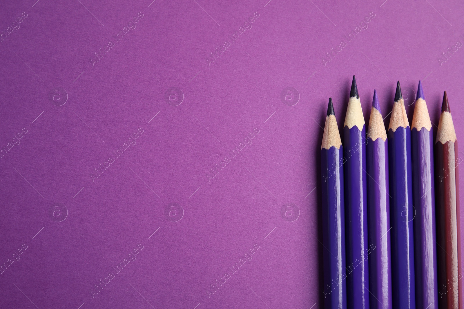 Photo of Flat lay composition with color pencils on purple background. Space for text